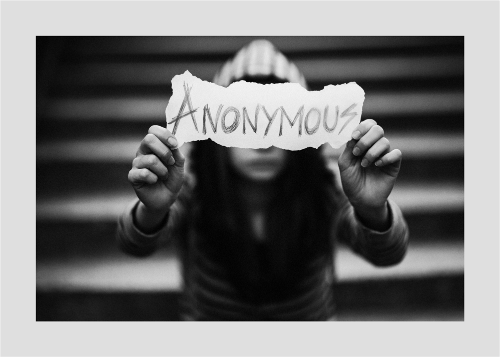 hidden child holding up anonymous sign